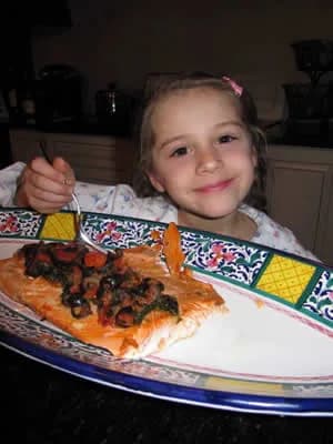 A girl eating a plate of salmon and spinach